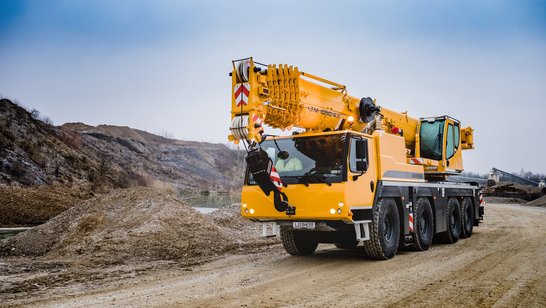 Yellow mobile telescopic crane on unpaved road