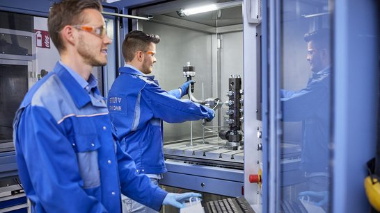 Two engineers testing hydraulic lines on the impulse test bench